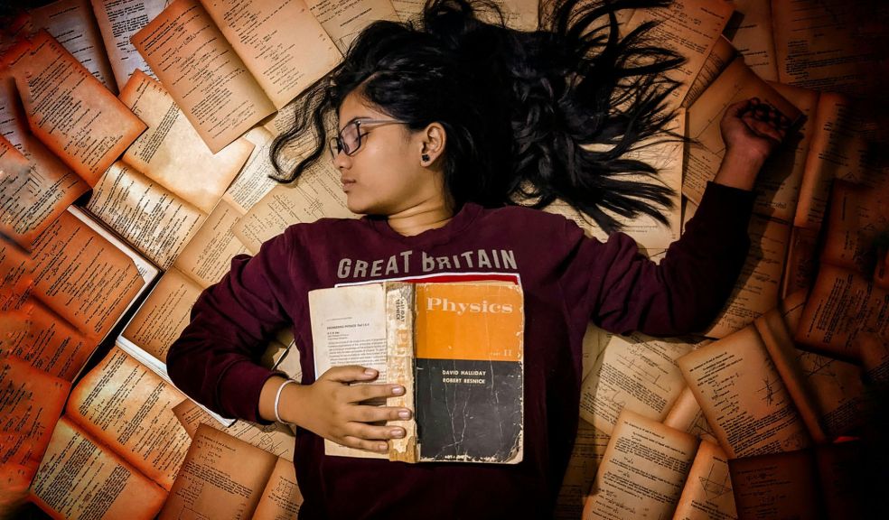 Exams. Girl lying on a pile of books.