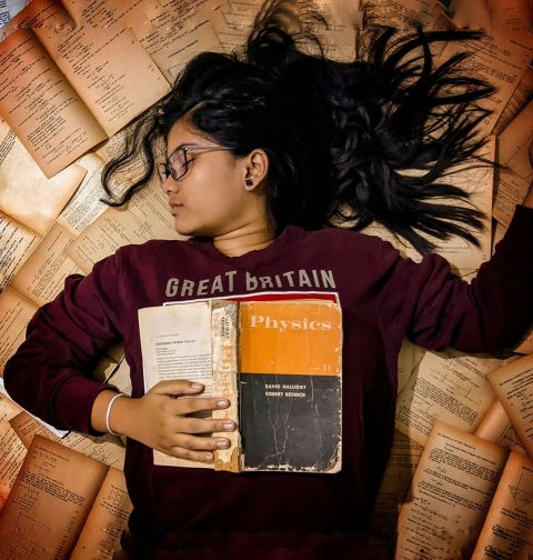 Exams. Girl lying on a pile of books.