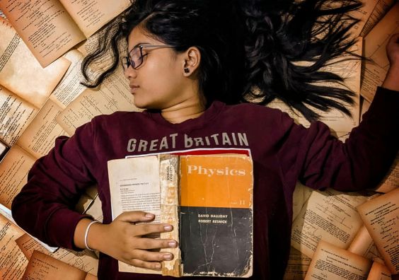 Exams. Girl lying on a pile of books.