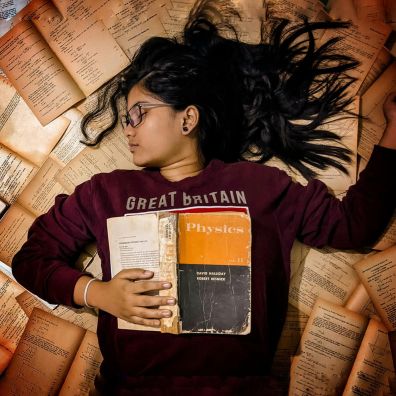 Exams. Girl lying on a pile of books.